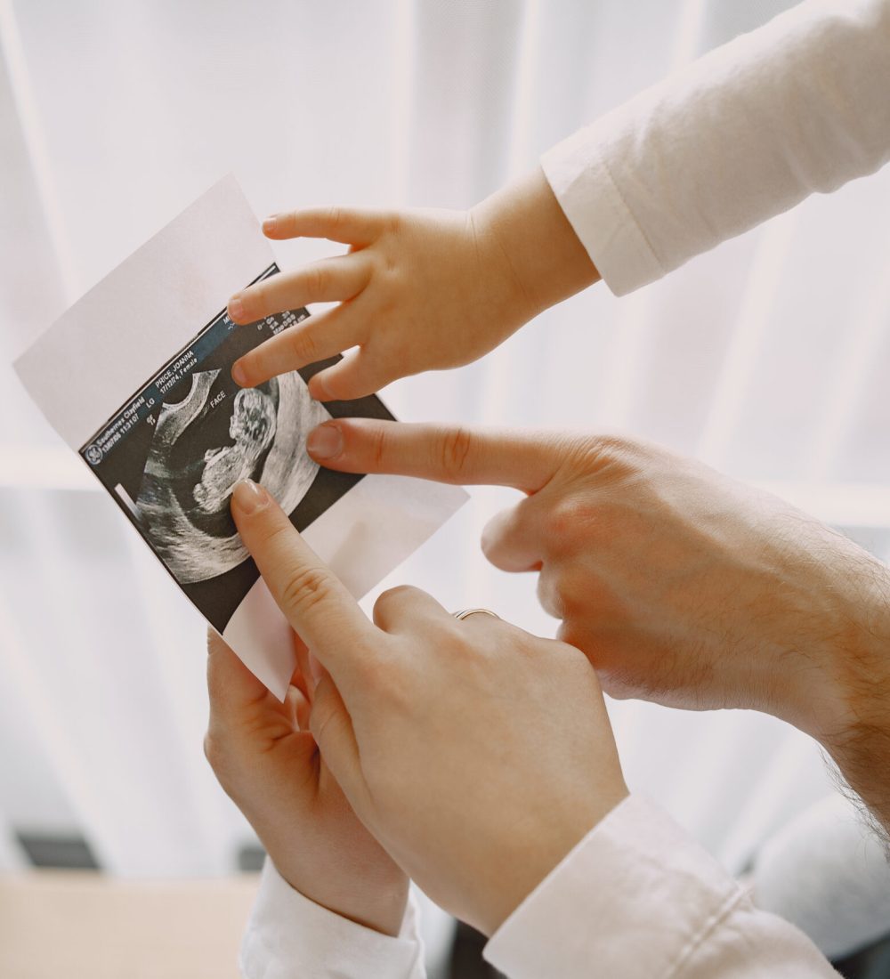 Mom dad and daughter watching photos. Family in light clothes. Family expecting a baby.