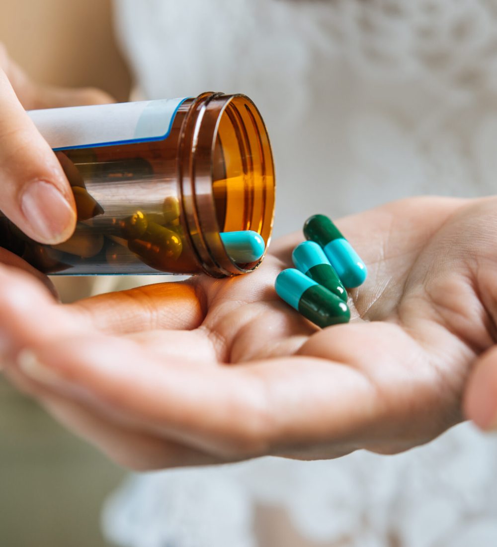 Woman's hand pours the medicine pills out of the bottle